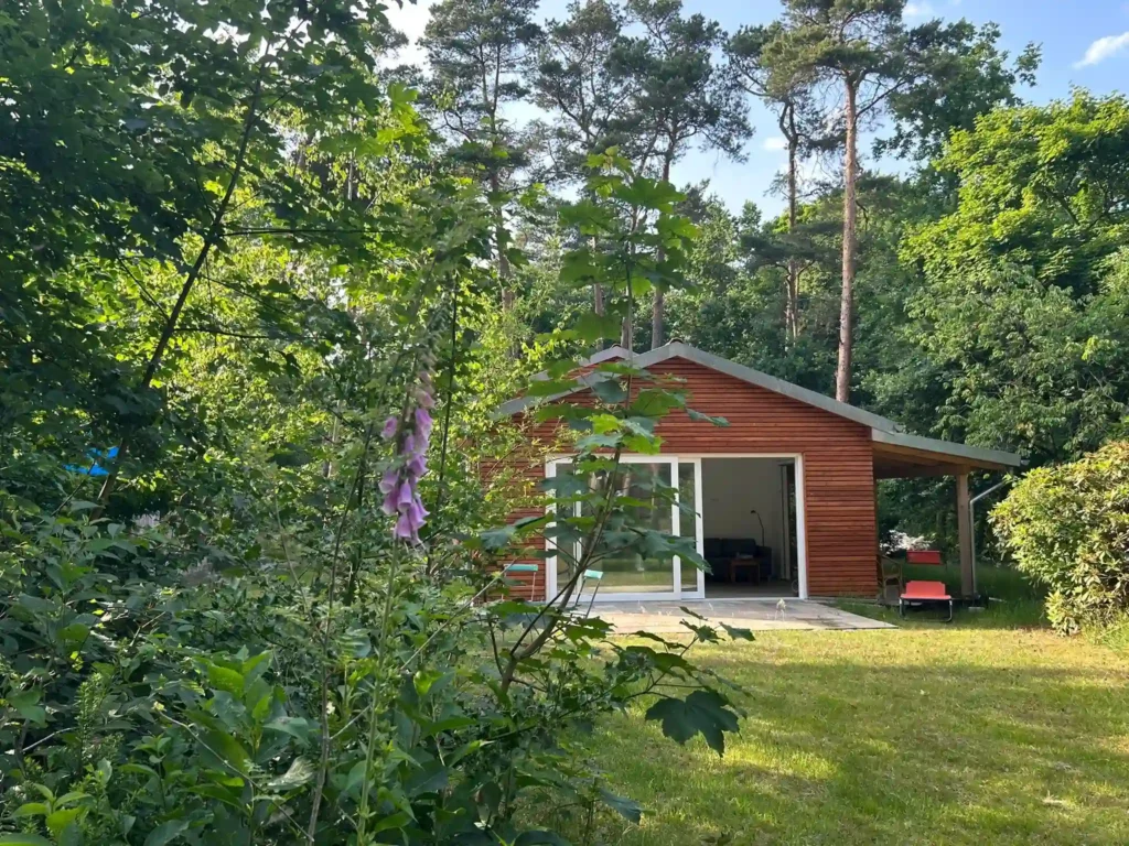 Sicht auf Ferienhaus am Weiher vom Garten. Man sieht die große Schiebetür zum Garten.